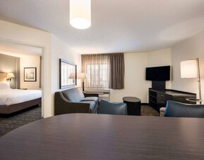 Sonesta Simply Suites Dallas Galleria double bed guest room, with lounge area that has a sofa, coffee table, and widescreen TV.