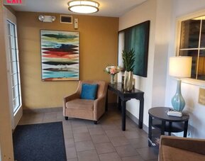 The hotel lobby has an armchair, potted plants, and art on the walls.