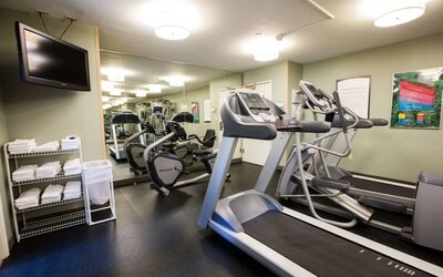 The fitness center at Sonesta ES Suites Austin The Domain Area includes a widescreen television, plenty of towels, and multiple exercise machines.