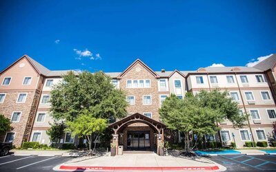 The hotel’s exterior has a covered entranceway flanked by trees, in addition to numerous parking spaces.
