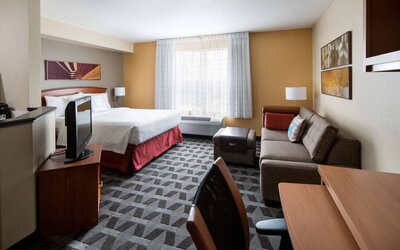 Sonesta Simply Suites Seattle Renton double bed guest room lounge, including sofa, TV, chair, and window.