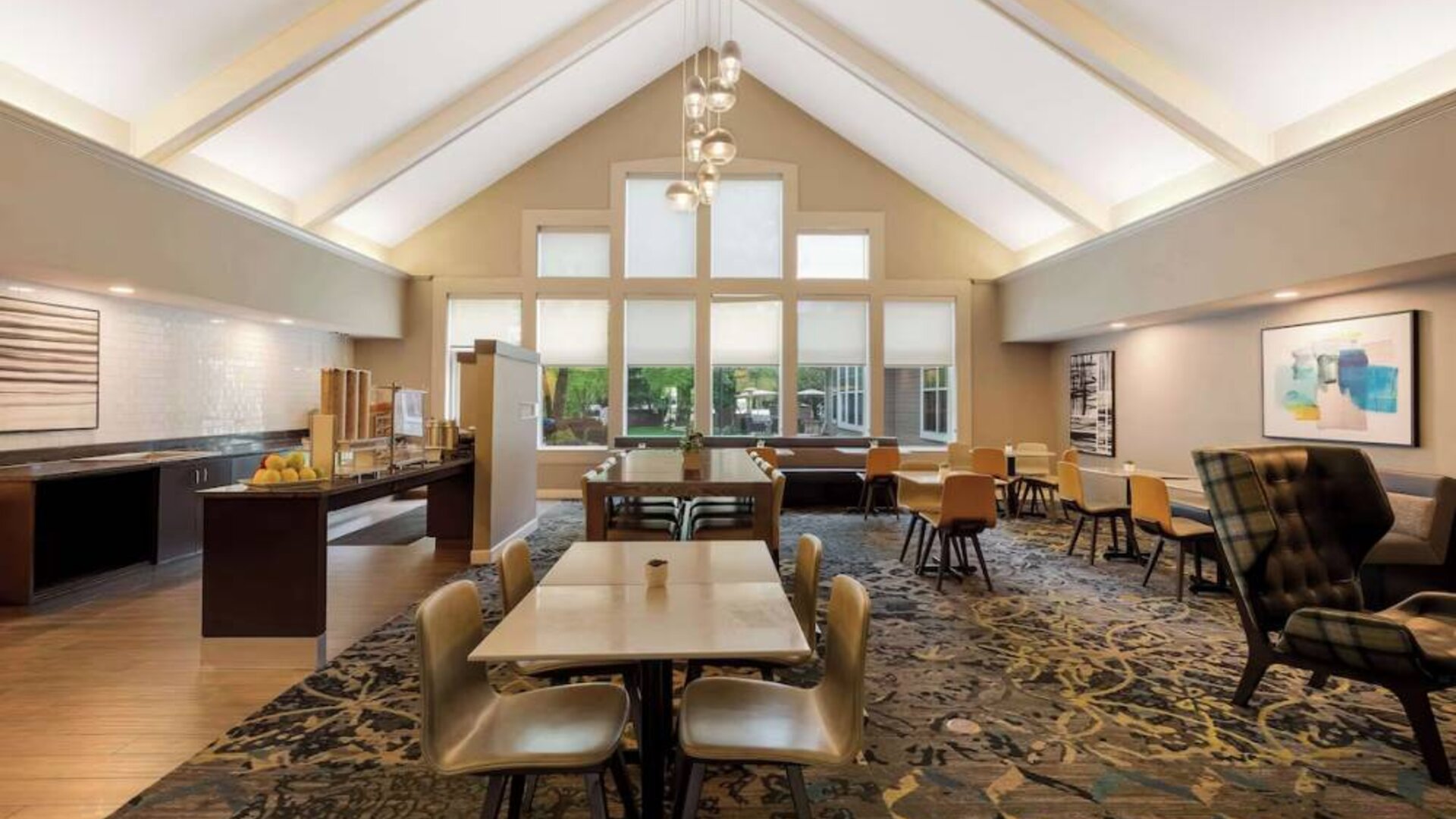 The hotel’s breakfast area is spacious and has large windows, with tables varying from two seats to eight, and art on the wall.