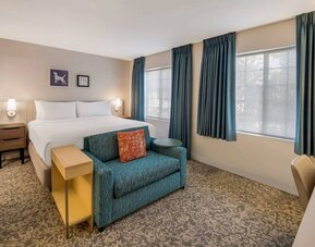Sonesta ES Suites Andover Boston double bed guest room, including sofa, coffee table, and two windows.