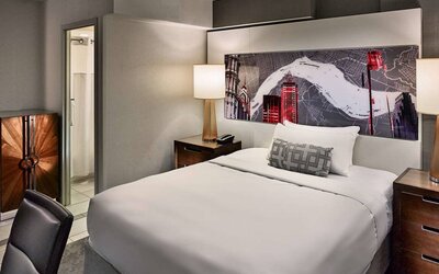 Sonesta Philadelphia Rittenhouse Square double bed guest room, featuring art on the wall, chair, and ensuite bathroom.