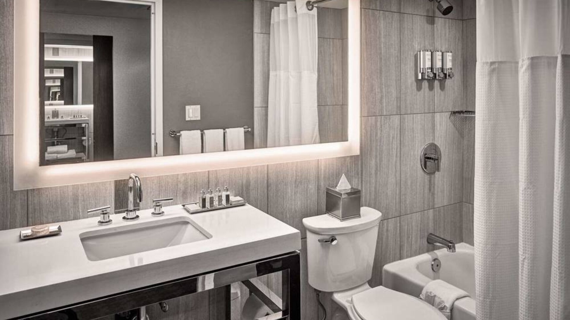 Guest bathroom in Sonesta Philadelphia Rittenhouse Square, equipped with sink and large mirror, lavatory, and bath with a shower.