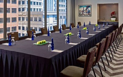 Sonesta Philadelphia Rittenhouse Square meeting room, featuring long table with space for over a dozen attendees, city views through the large windows, and art on the wall.