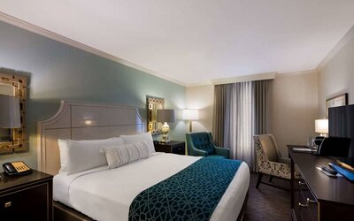 Double bed guest room in Royal Sonesta New Orleans, featuring television, armchair, and a workspace desk and chair.