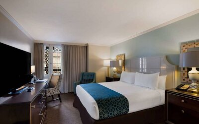 Royal Sonesta New Orleans double bed guest room, furnished with armchairs, desk, and a television.