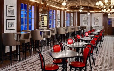 Guests can dine at the hotel restaurant, which has a mosaic-style floor, small tables, and a mix of regular and tall stool seating.