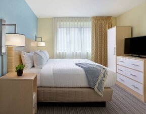 Double bed guest room in Sonesta ES Suites New Orleans, featuring bedside cabinet, widescreen TV, and large window.