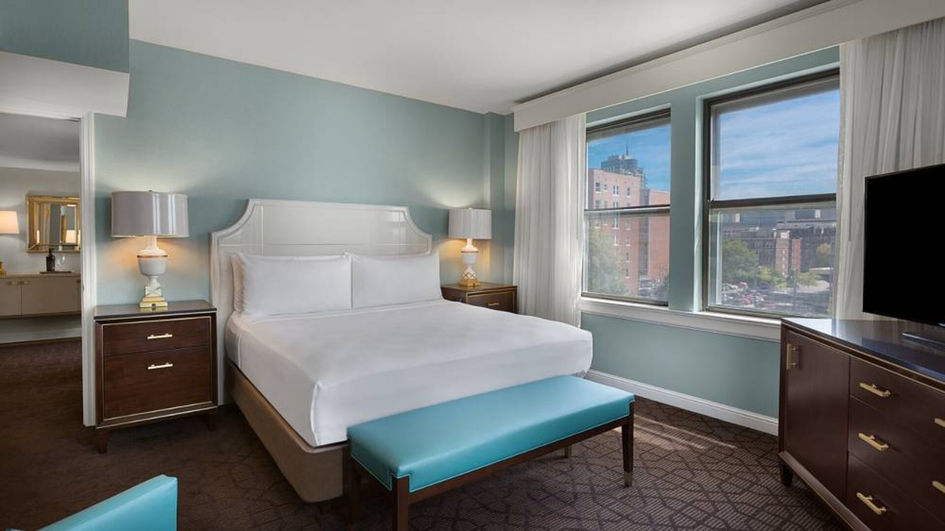 Double bed guest room in The Chase Park Plaza Royal Sonesta St. Louis, featuring armchair, windows, and TV.