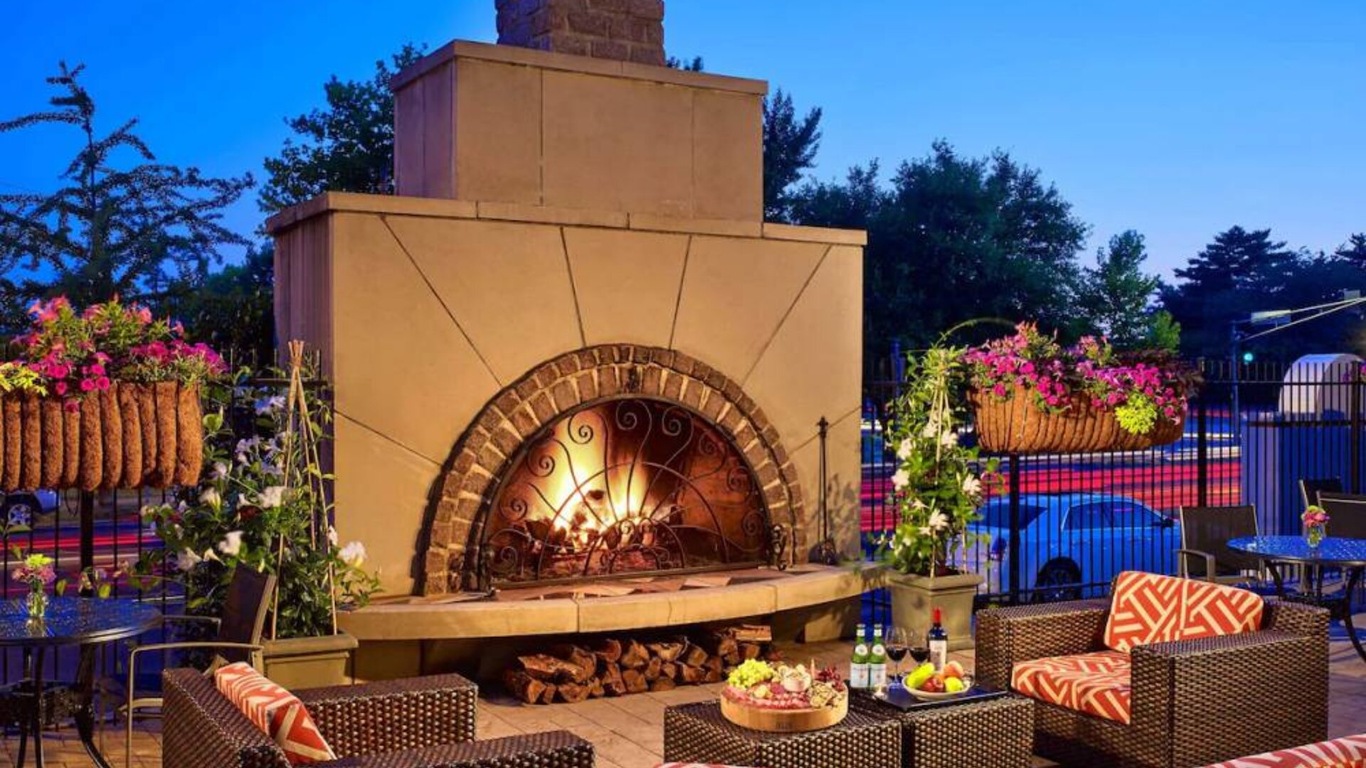 The outdoor fireplace at The Chase Park Plaza Royal Sonesta St. Louis has comfortable sofa and armchair seating nearby, in addition to coffee tables and beautiful flowers.