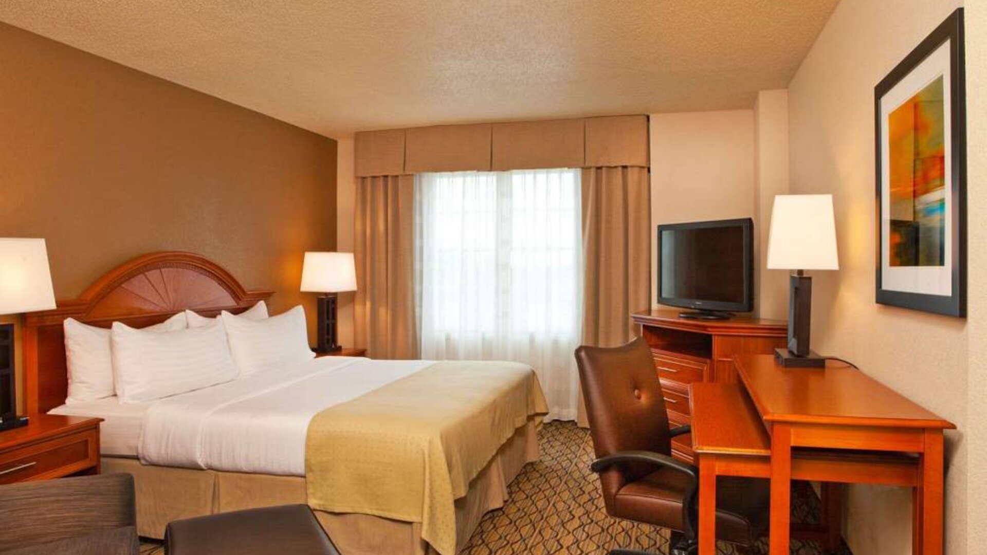 Double bed guest room in Sonesta Atlanta Airport South, featuring TV, window, and workspace desk and chair.