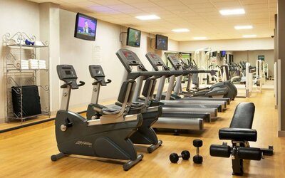 The fitness center at Sonesta Atlanta Airport North includes plenty of towels, free weights, and various types of exercise machines, plus multiple wall-mounted TVs.