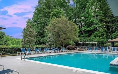 The outdoor pool at Sonesta Charlotte Executive Park has chairs by the side, is close to the fire pit, and connects directly to the indoor pool.