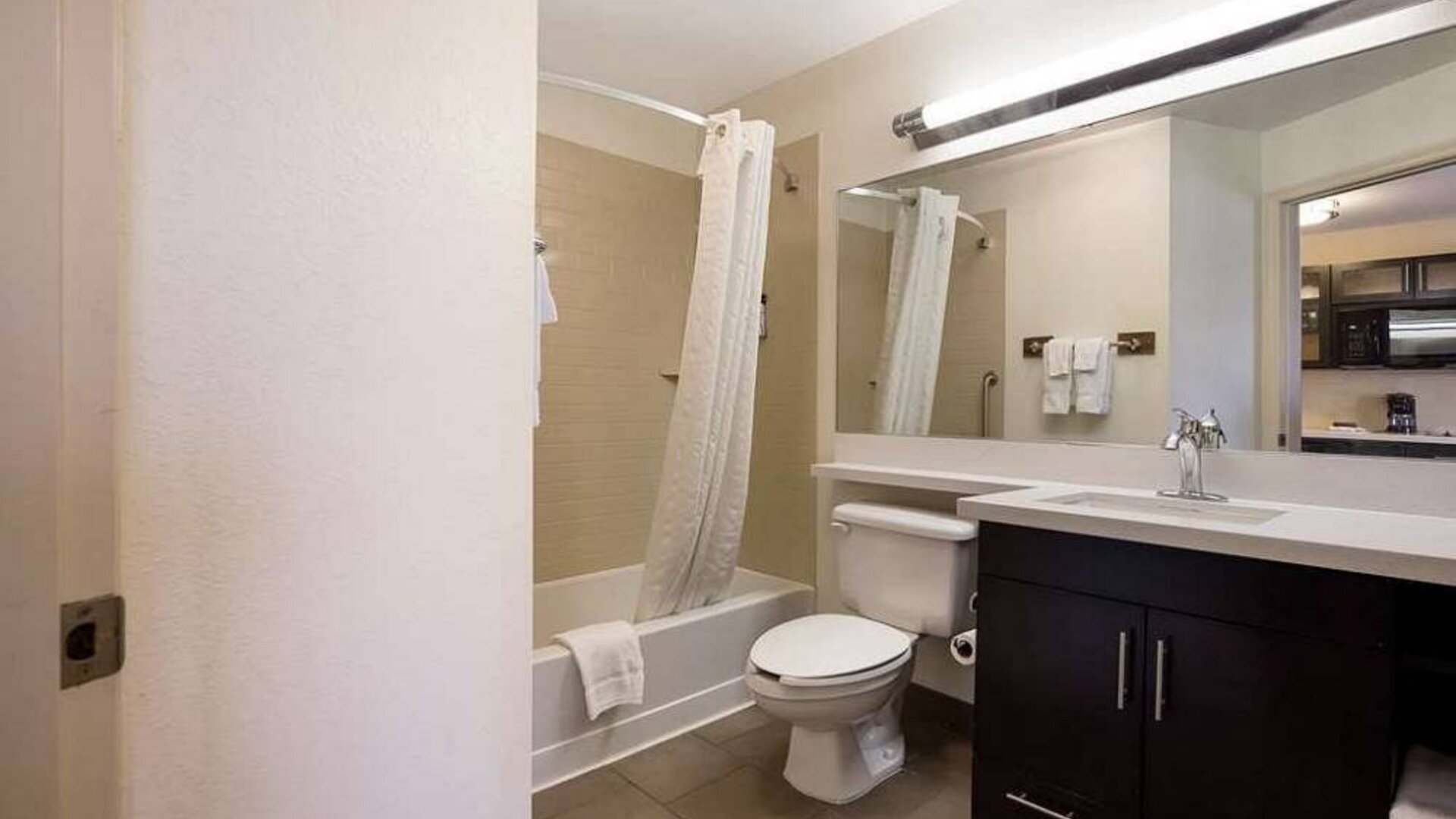 Guest bathroom in Sonesta Simply Suites St Louis Earth City, with bath, lavatory, long mirror, and sink.