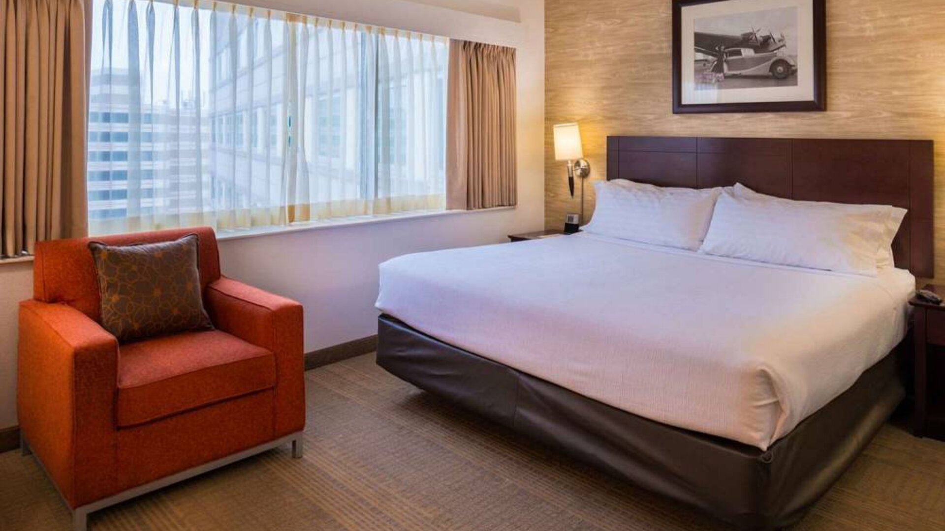 Double bed guest room in Sonesta Chicago O'Hare Airport Rosemont, including window, bedside light, and an armchair.