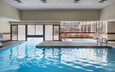 The hotel’s indoor pool has an adjacent hot tub and large windows, with a direct water link to the outdoor pool. 