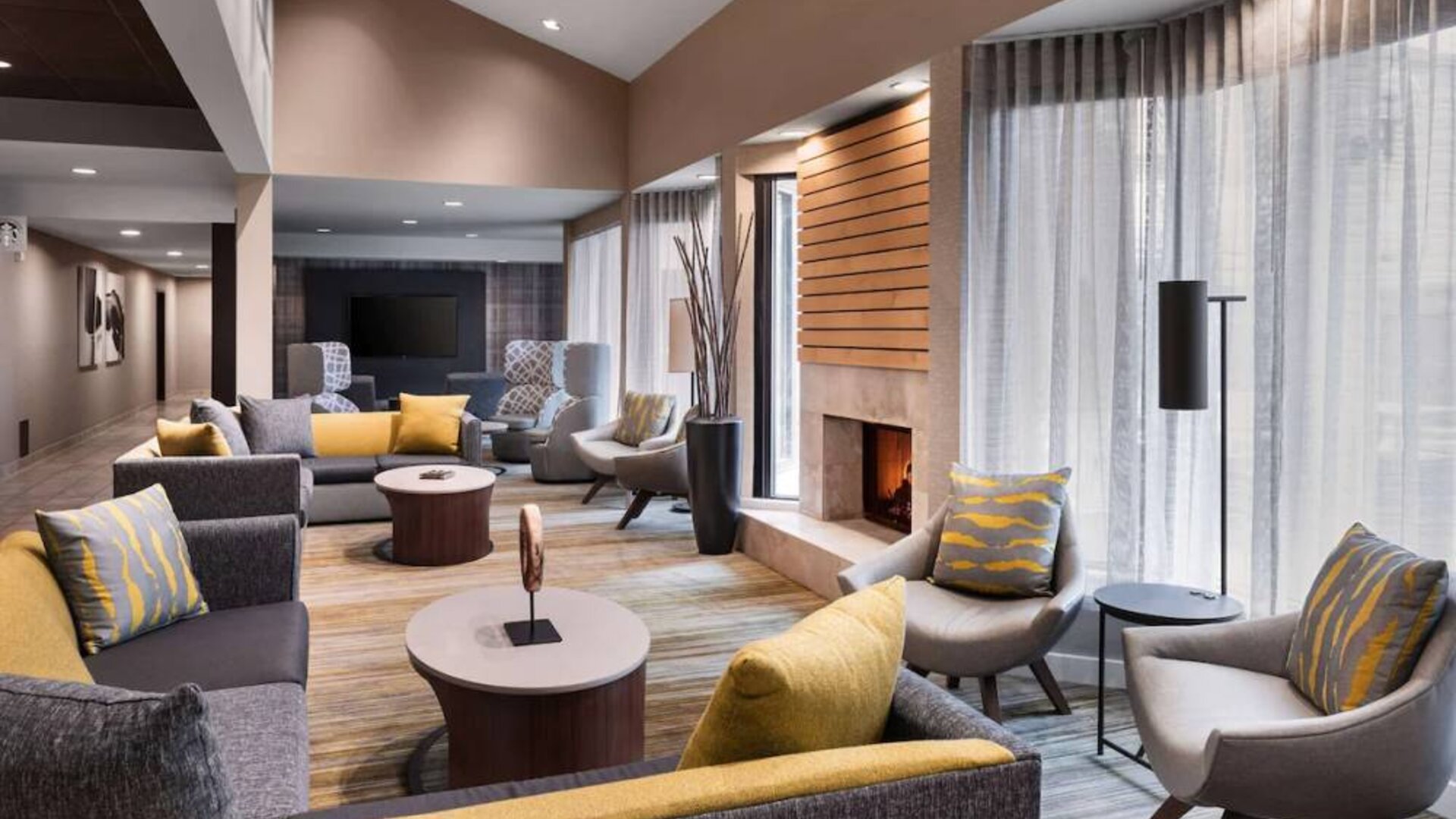 Sonesta Select Newport Middletown’s lobby lounge is furnished with comfy chairs and corners sofas, a fireplace and coffee tables, plus large windows.