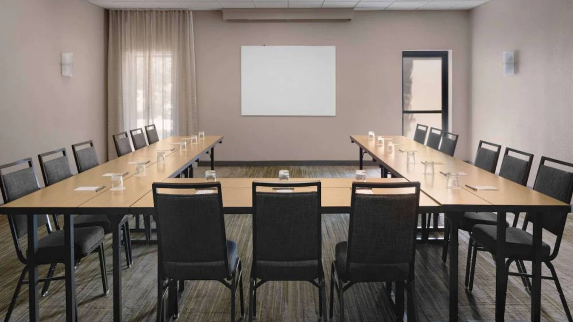 Meeting room in Sonesta Select Newport Middletown, with tables arranged in a U-shape facing a large whiteboard.