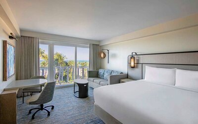 Double bed guest room in Royal Sonesta San Juan, featuring table, chairs, coffee table, and a sofa, plus balcony.