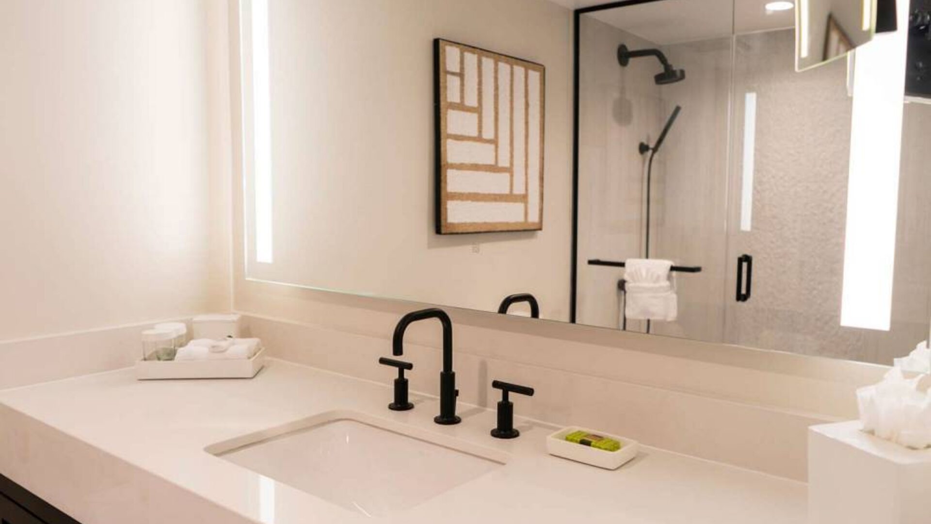 Royal Sonesta San Juan guest bathroom, including shower, sink, and mirror, plus art on the wall.