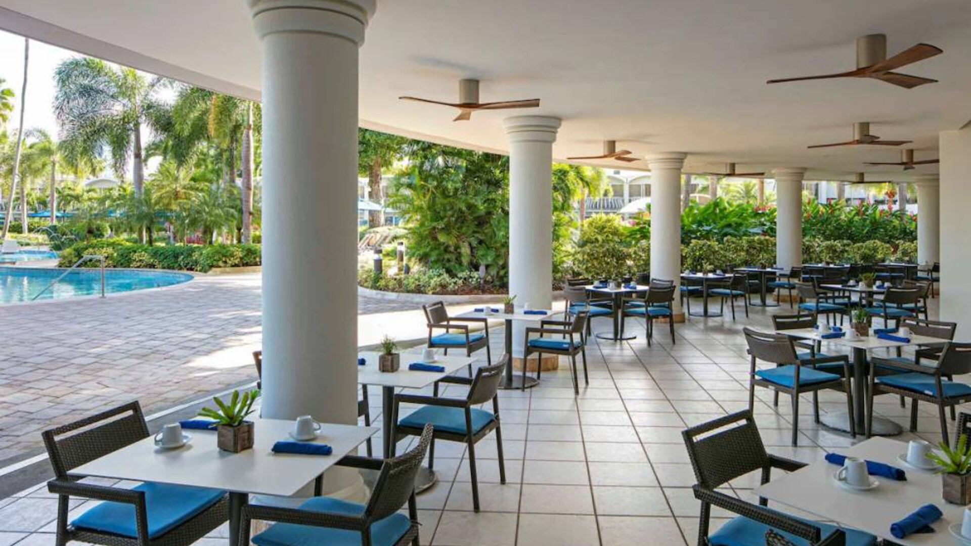 The hotel’s breakfast area has a hard floor, numerous ceiling fans, and small tables within easy reach of the pool.