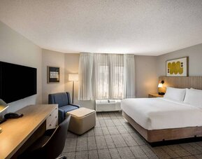 Sonesta Simply Suites Jersey City double bed guest room, featuring armchair, window, and widescreen television.