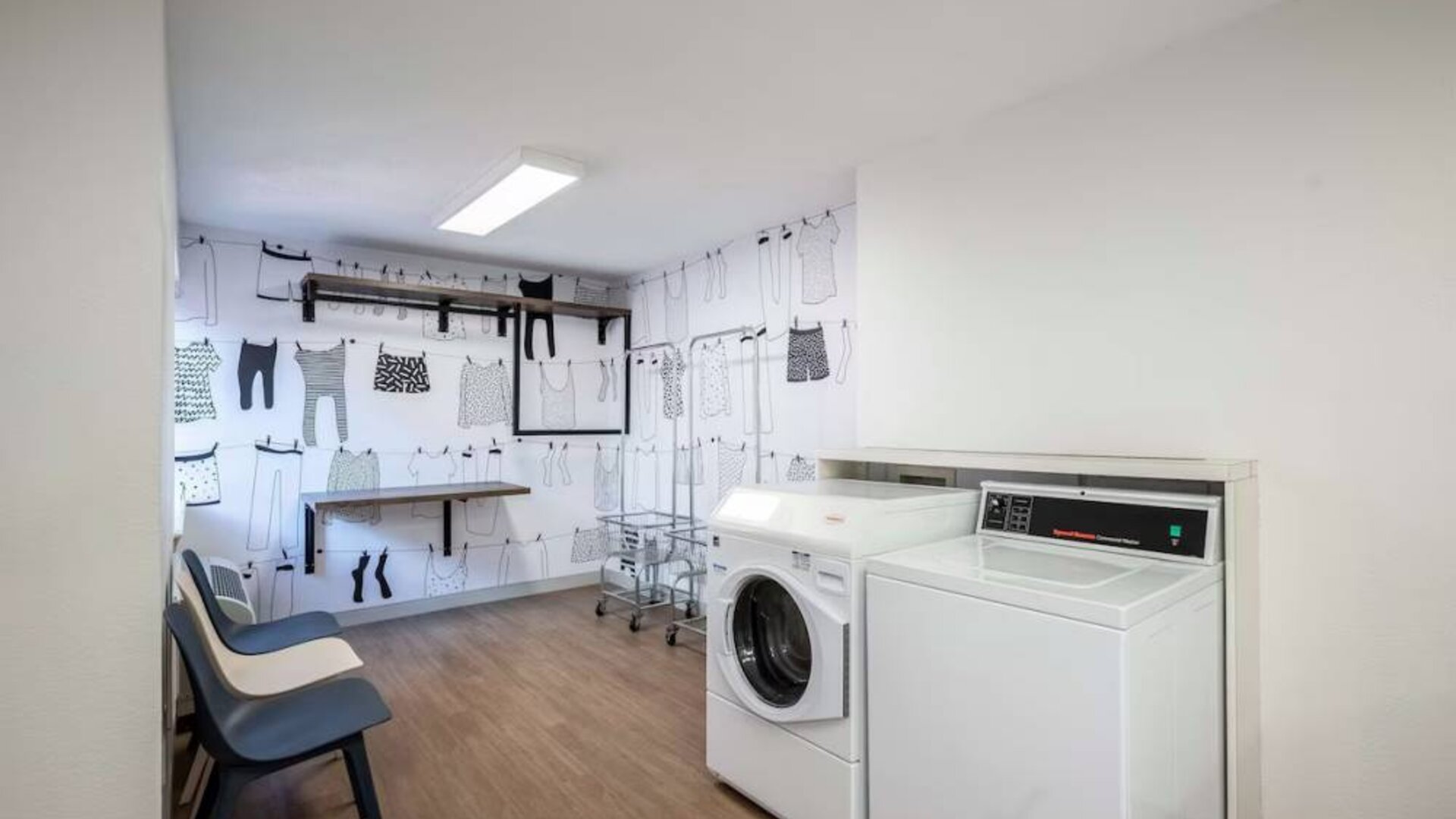 The hotel’s laundry room features a washer and drier, a pair of baskets, plus shelves and chairs.