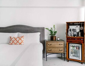 Nautilus by Sonesta double bed guest room, featuring bedside chest of drawers and drinks facilities including a mini-fridge.