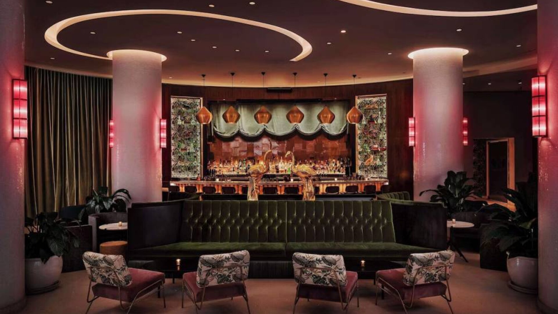 The lobby bar of Nautilus by Sonesta has a mix of traditional bar stool and more relaxed seating, numerous potted plants and subdued lighting.