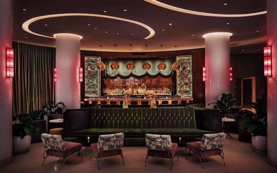 The lobby bar of Nautilus by Sonesta has a mix of traditional bar stool and more relaxed seating, numerous potted plants and subdued lighting.