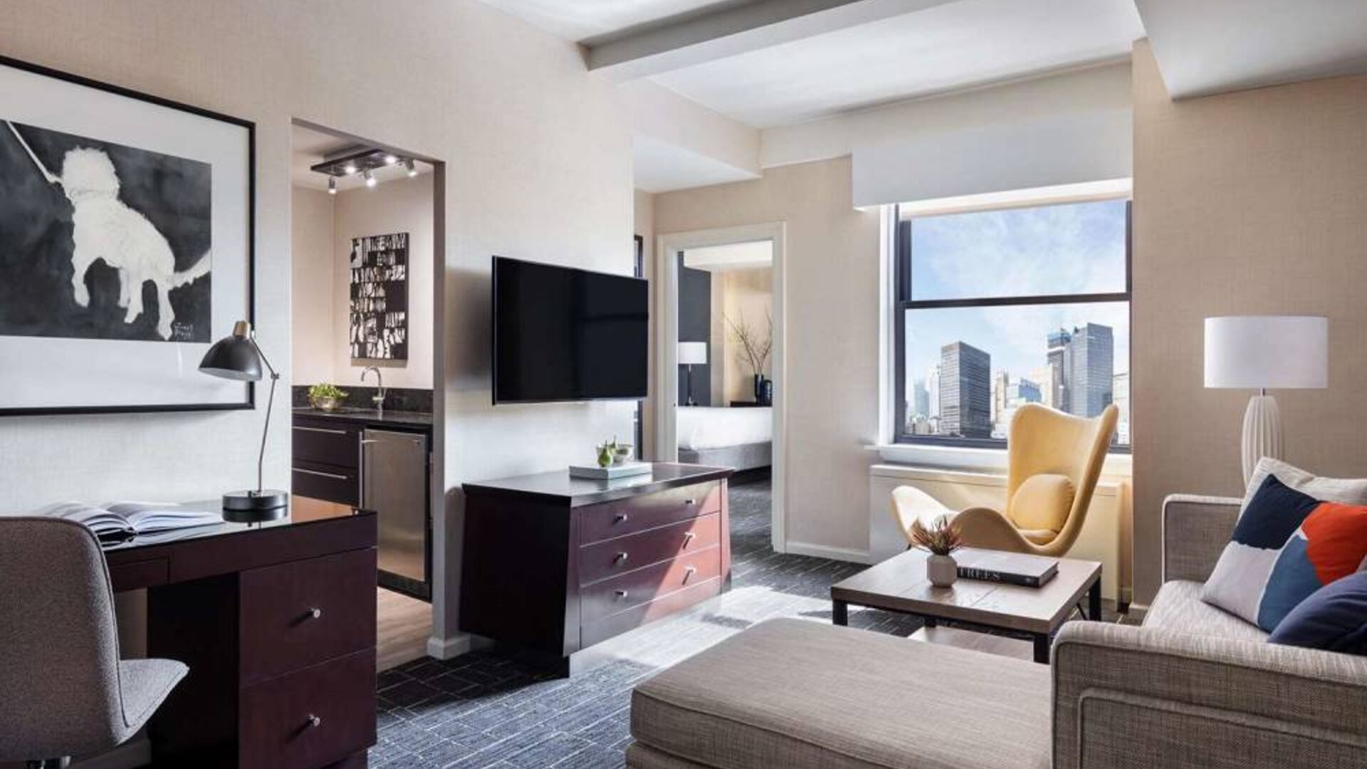 The Shelburne Sonesta New York guest room living area, including sofa, chairs, coffee table, and TV.