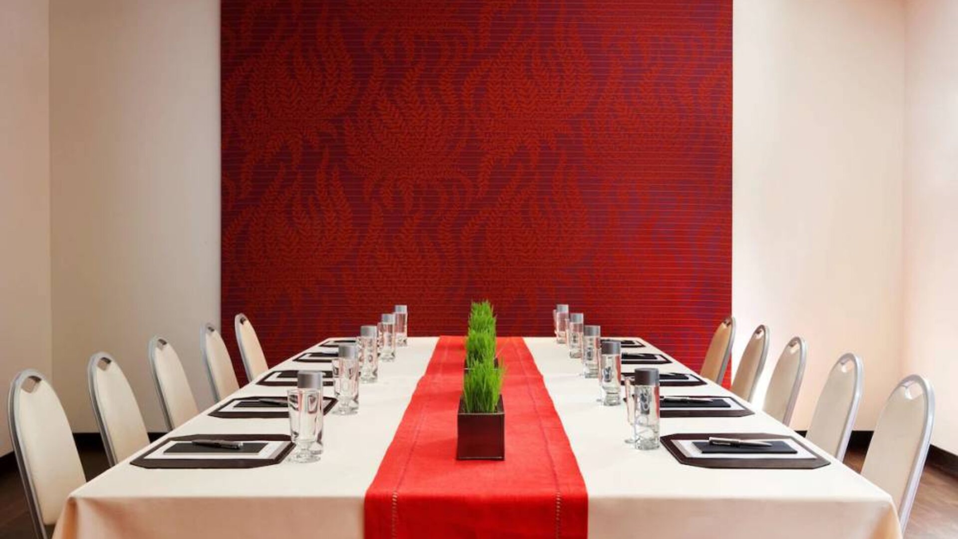 Meeting room in The Shelburne Sonesta New York, furnished with long table, 10 chairs around it, and a stark white and red color scheme.