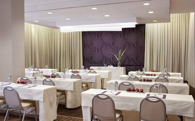 The Shelburne Sonesta New York meeting room with tables arranged in a classroom style facing a head table and space for over a dozen attendees.