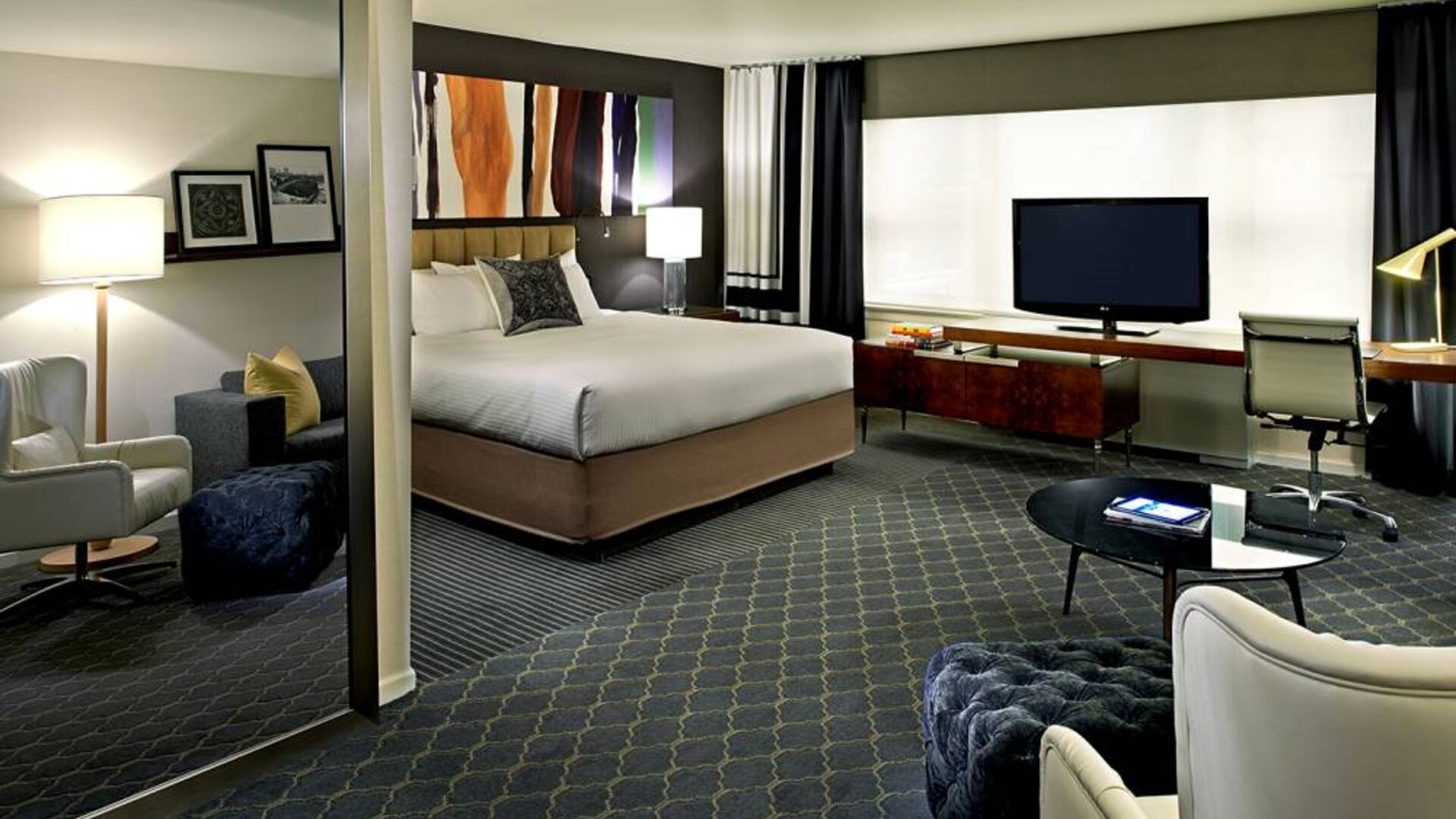 The Fifty Sonesta Select New York double bed guest room, including desk and chair, coffee table, window, and widescreen TV.