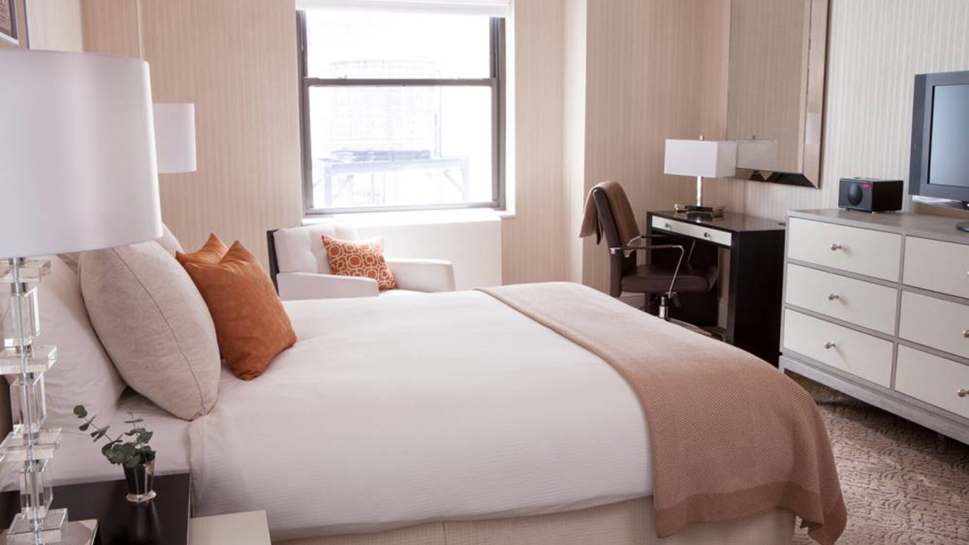 Double bed guest room in The Benjamin Royal Sonesta New York, furnished with TV, armchair, and workspace desk and chair.