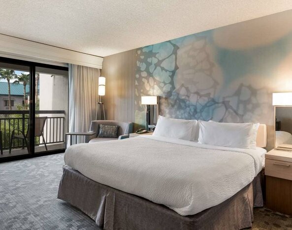 Double bed guest room in Sonesta Select Tempe Downtown, featuring armchair, coffee table, and balcony.