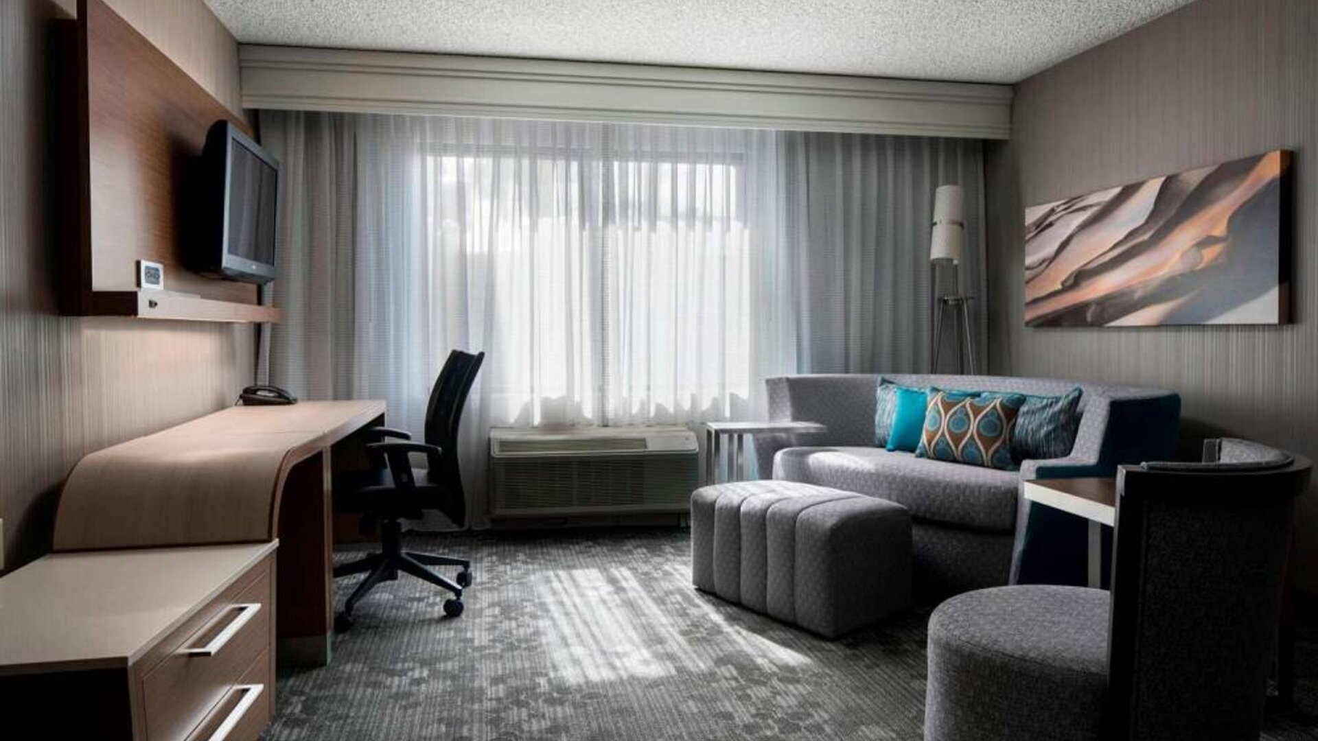 Sonesta Select Tempe Downtown guest room living area, including window, chairs, TV, and sofa.