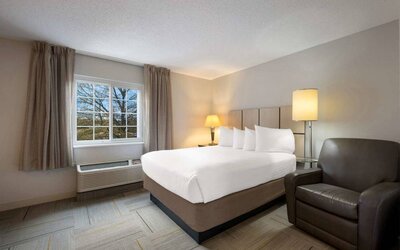 Double bed guest room in Sonesta Simply Suites Huntsville Research Park, including a window and armchair.