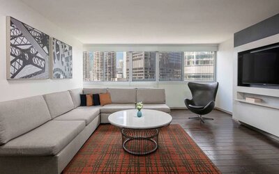 Royal Sonesta Chicago Downtown guest room lounge, with large sofa, chair, and coffee table, plus a wall-mounted TV.
