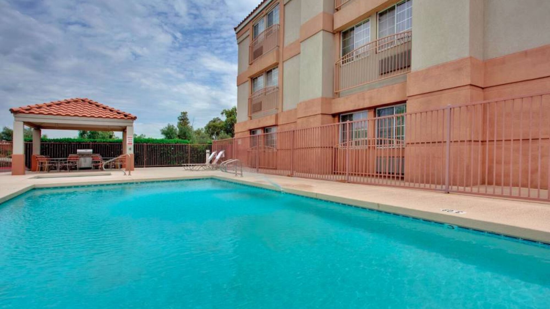 The outdoor pool at Sonesta Simply Suites Phoenix Tempe has sun loungers by the side, and is close to the gazebo and barbecue facilities.