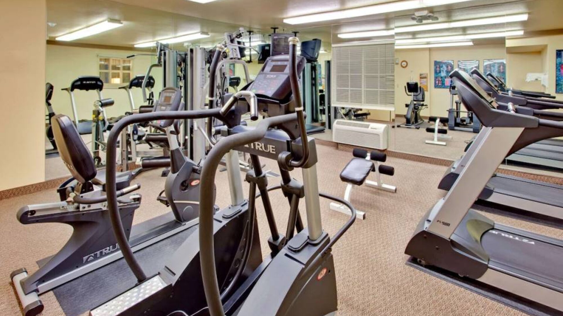 Sonesta Simply Suites Phoenix Tempe’s fitness center has a mirrored wall and a range of exercise equipment.