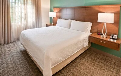 Double bed guest room in Sonesta ES Suites Fort Lauderdale Plantation, including bedside lamps and a window.