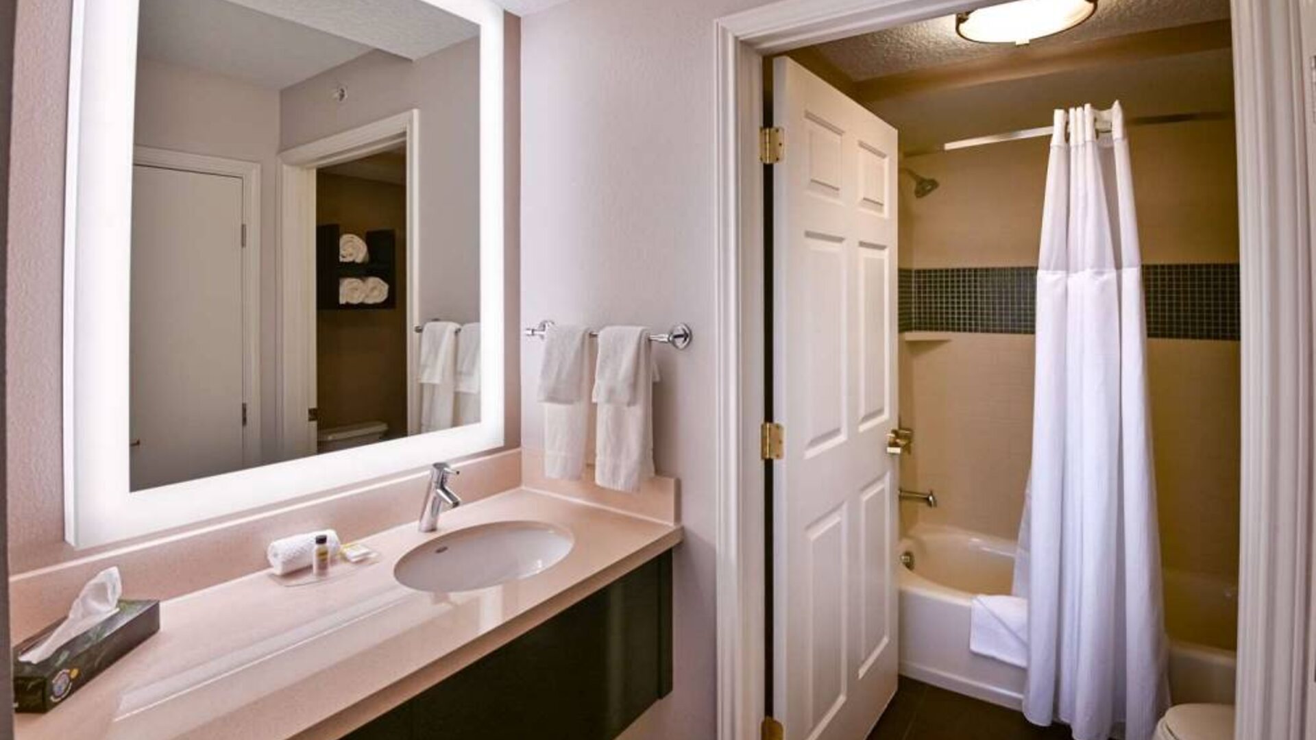 Guest bathroom in Sonesta ES Suites Fort Lauderdale Plantation, with shower-equipped bath, lavatory, mirror, and sink.