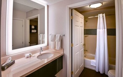 Guest bathroom in Sonesta ES Suites Fort Lauderdale Plantation, with shower-equipped bath, lavatory, mirror, and sink.