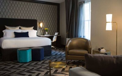 The Allegro Royal Sonesta Hotel Chicago Loop double bed guest room, furnished with workspace desk and chair, window, and an armchair and coffee table.