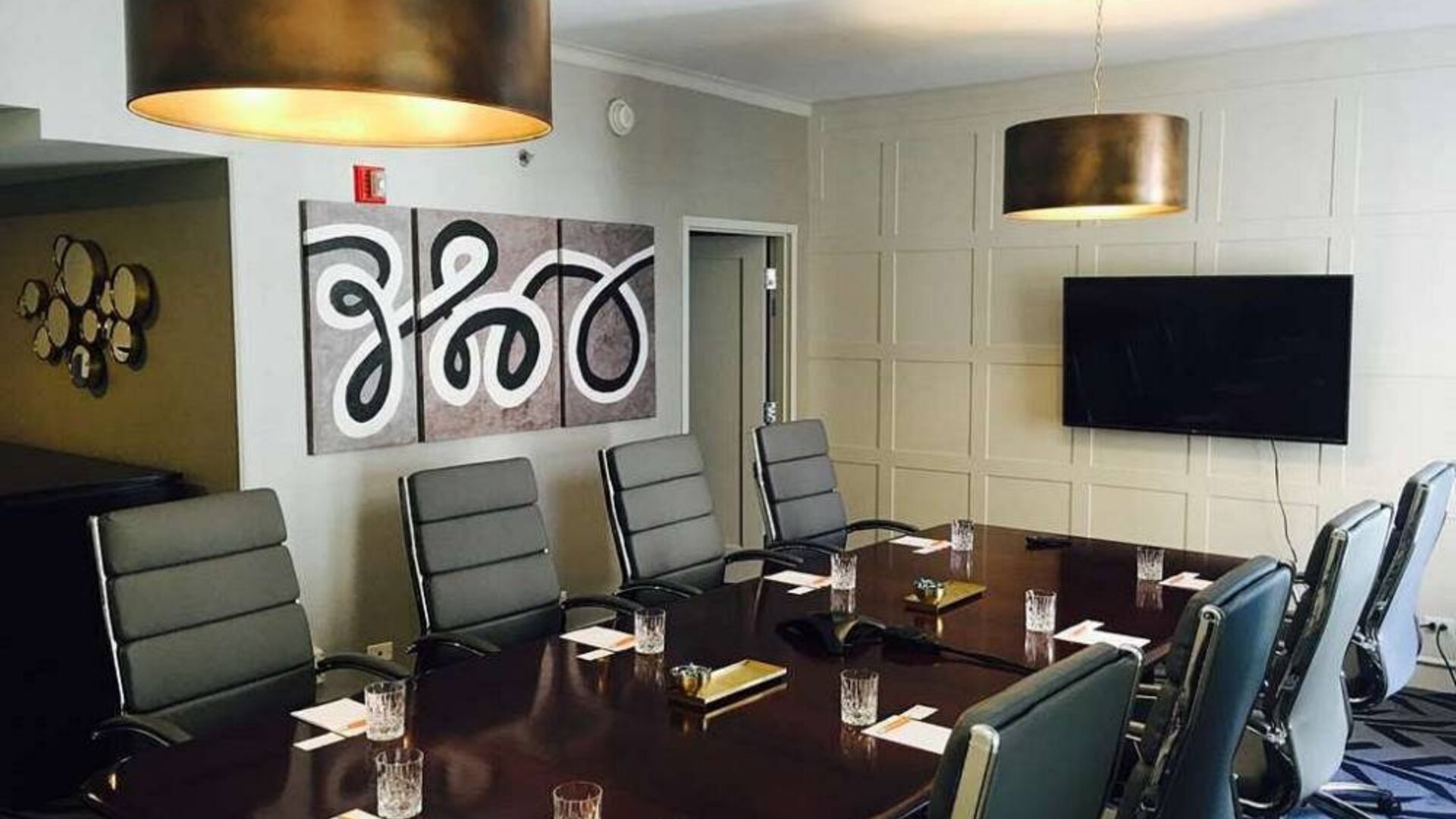 The Allegro Royal Sonesta Hotel Chicago Loop meeting room, with long wooden table, art on one wall and a large TV on the other.