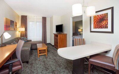 Sonesta ES Suites Atlanta - Perimeter Center double bed guest room, with living area that has a desk and chair, sofa, coffee tables, window, and TV.
