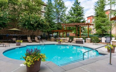Sonesta ES Suites Atlanta - Perimeter Center’s round outdoor pool has potted plants and sun loungers nearby, with tables and chairs close at hand.